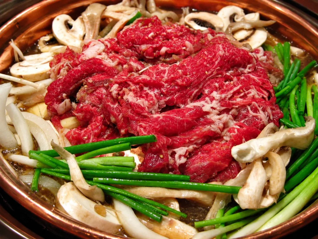 Korean beef bulgogi with vegetables on a copper grill