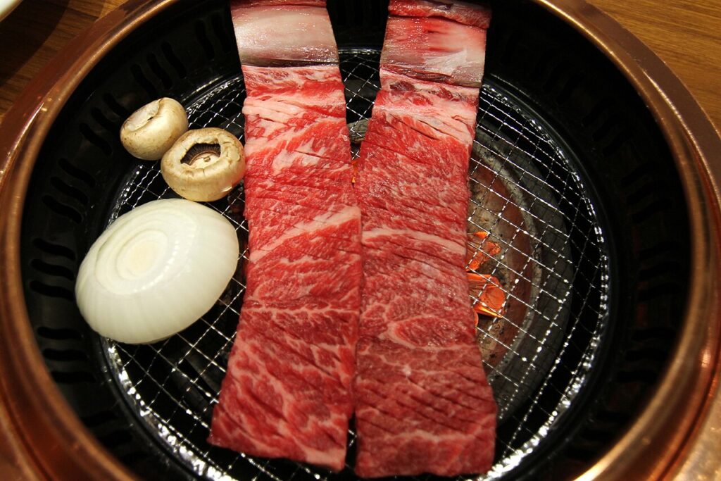 Beef ribs grilling over a Korean BBQ grill at a restaurant.